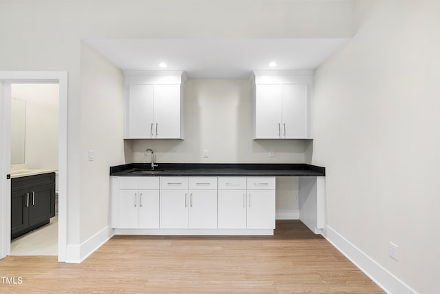 kitchen with white cabinetry, sink, and light hardwood / wood-style floors