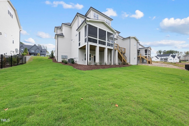 back of property with a lawn, a sunroom, and central air condition unit