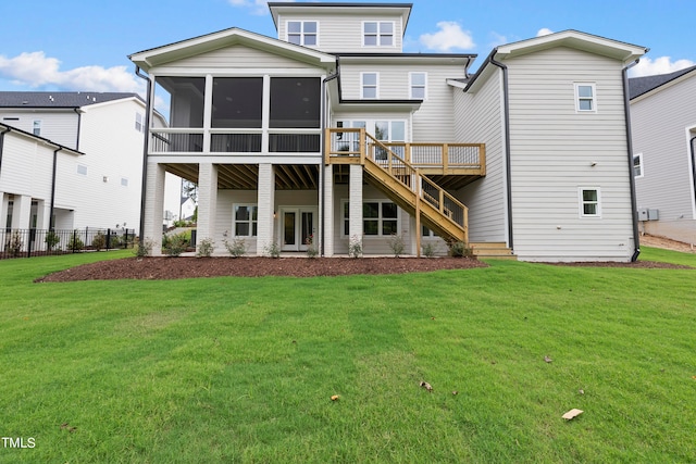 rear view of property featuring a lawn, a sunroom, and a deck