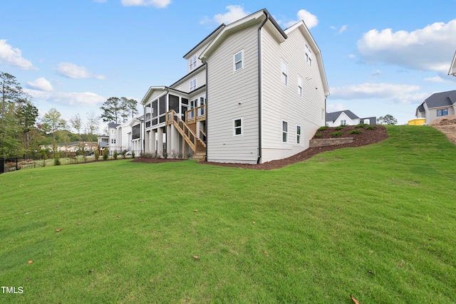 rear view of house featuring a yard and a sunroom