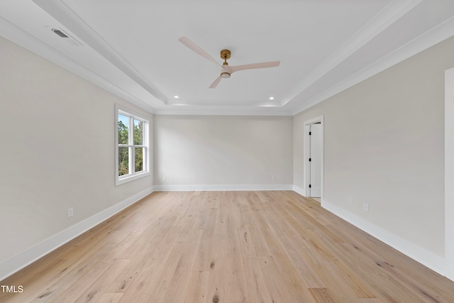 empty room featuring a tray ceiling, light hardwood / wood-style flooring, ornamental molding, and ceiling fan