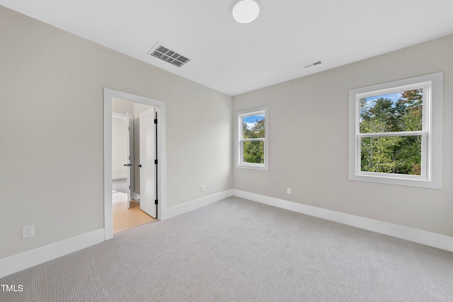 unfurnished bedroom featuring connected bathroom and light colored carpet