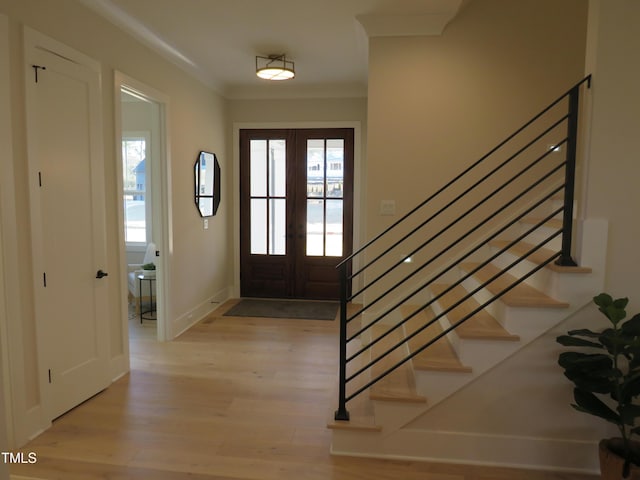 entrance foyer with a wealth of natural light, light hardwood / wood-style flooring, ornamental molding, and french doors