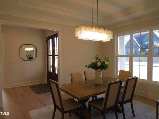 dining space with hardwood / wood-style flooring, crown molding, and a tray ceiling