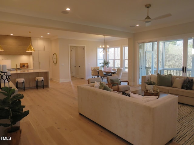 living room with ceiling fan with notable chandelier and light hardwood / wood-style flooring