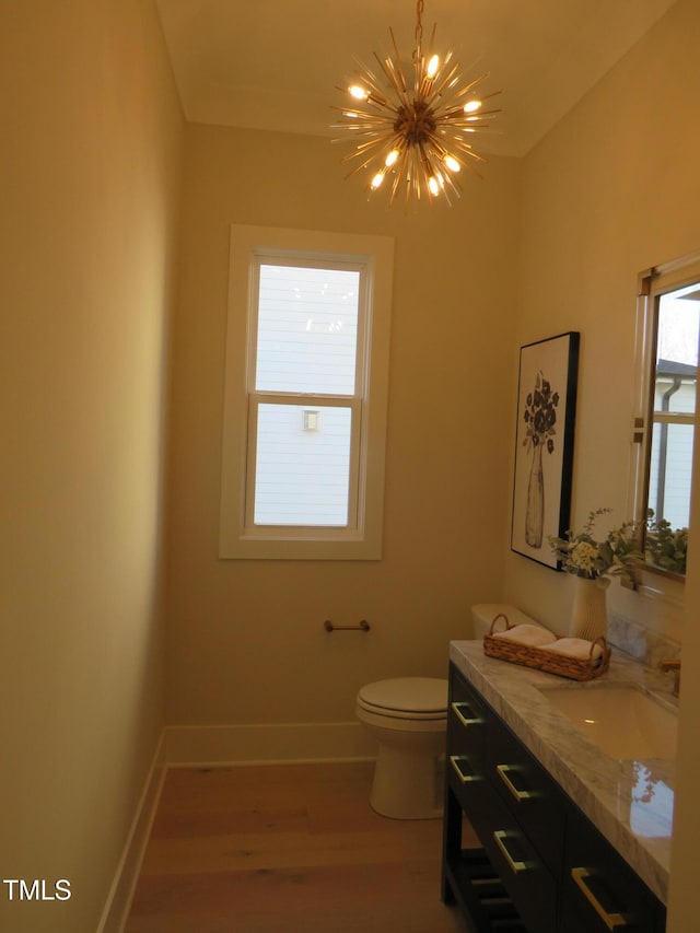 bathroom featuring an inviting chandelier, vanity, hardwood / wood-style floors, and toilet