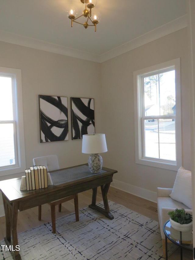 office space featuring ornamental molding, a healthy amount of sunlight, an inviting chandelier, and light hardwood / wood-style floors