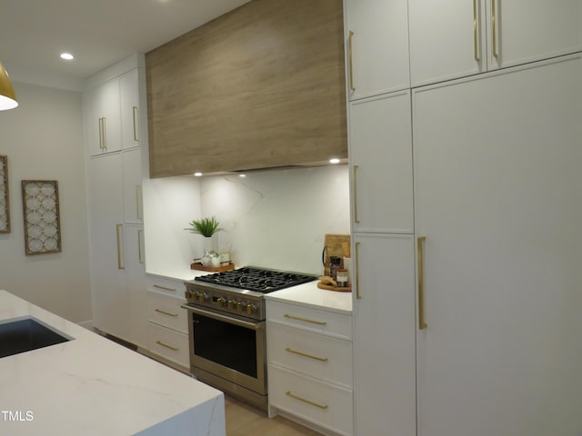 kitchen with white cabinetry, light stone countertops, and stainless steel stove