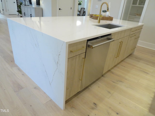 kitchen featuring light wood-type flooring, sink, an island with sink, and light brown cabinets