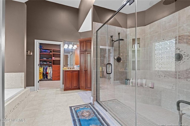 bathroom featuring vanity, a towering ceiling, tile flooring, and plus walk in shower