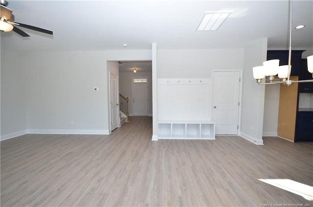 unfurnished living room with ceiling fan with notable chandelier and light hardwood / wood-style floors