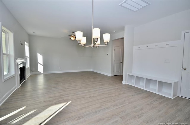 unfurnished living room featuring ceiling fan with notable chandelier and light hardwood / wood-style floors