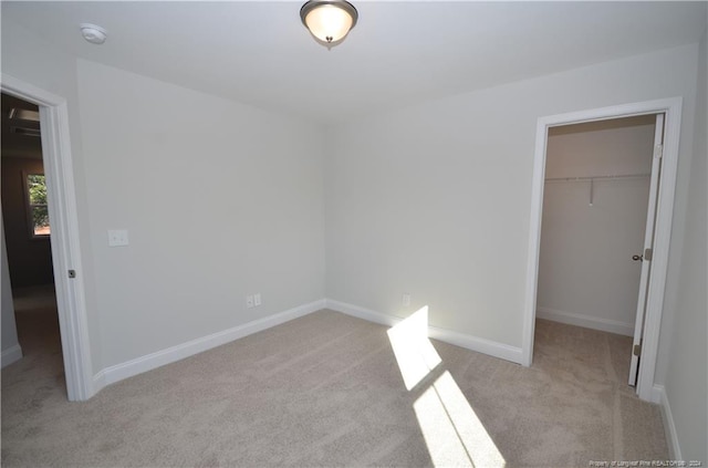 unfurnished bedroom with light colored carpet, a spacious closet, and a closet