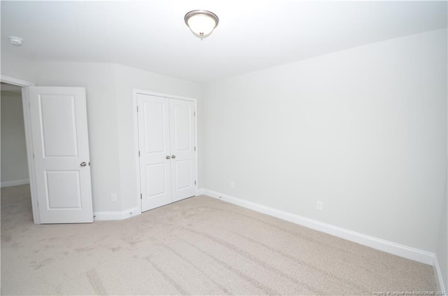 unfurnished bedroom with light colored carpet and a closet