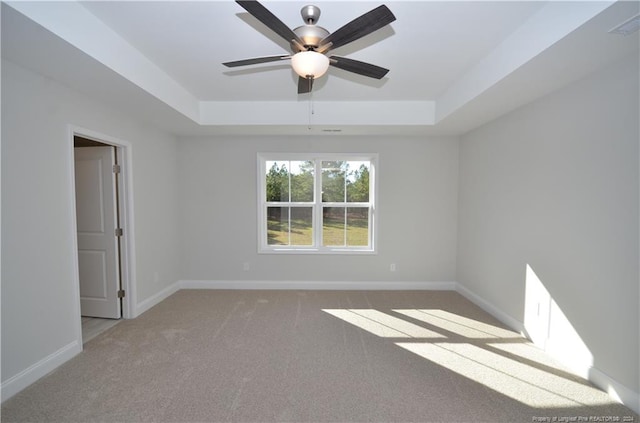 carpeted spare room with ceiling fan and a tray ceiling