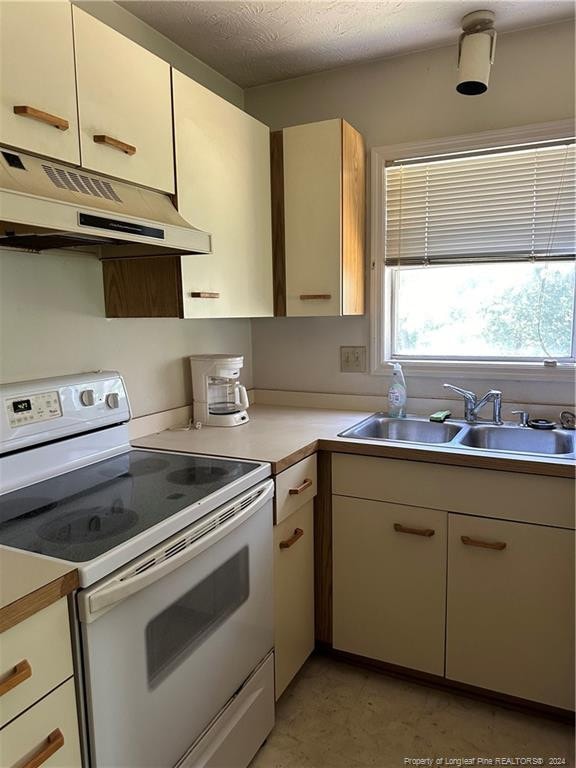 kitchen featuring white range with electric cooktop, sink, light tile patterned flooring, and a textured ceiling