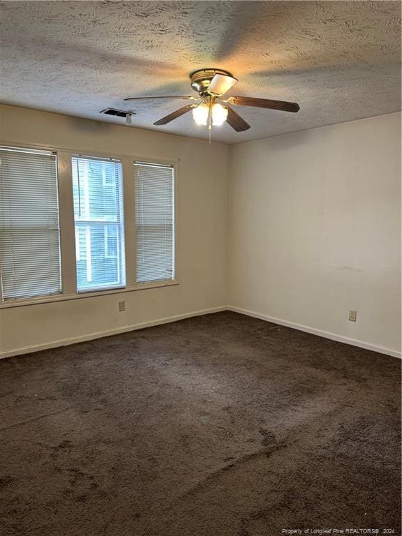 unfurnished room featuring a textured ceiling, dark carpet, and ceiling fan