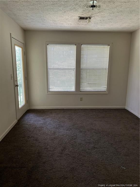 carpeted empty room with a textured ceiling