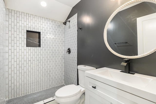 bathroom featuring vaulted ceiling, tiled shower, vanity, and toilet