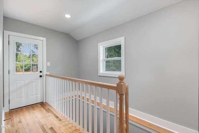 doorway to outside featuring vaulted ceiling, a healthy amount of sunlight, and light hardwood / wood-style floors