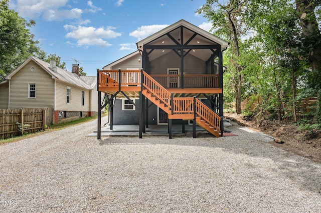 back of house featuring a wooden deck, a sunroom, and a patio