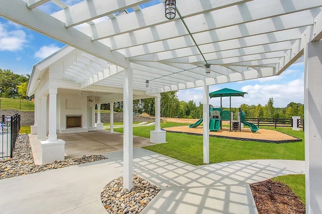 view of patio / terrace with exterior fireplace, a pergola, and a playground