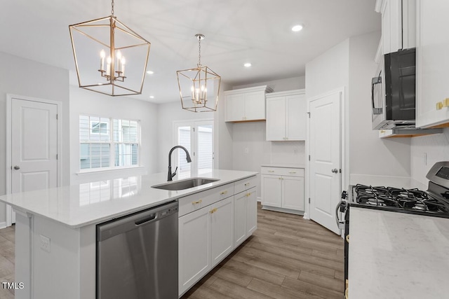 kitchen with pendant lighting, sink, white cabinetry, stainless steel appliances, and an island with sink