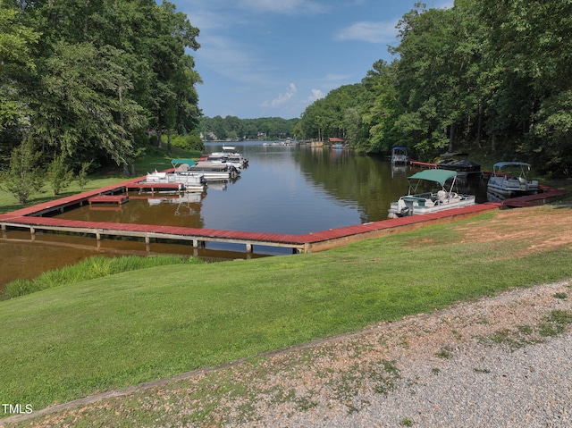 view of dock with a lawn and a water view