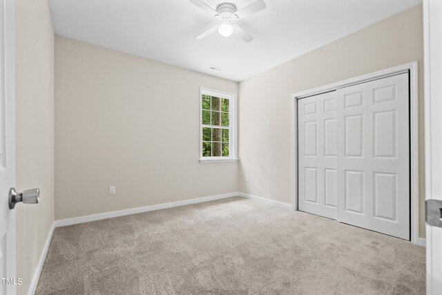 unfurnished bedroom featuring a closet, ceiling fan, and light colored carpet