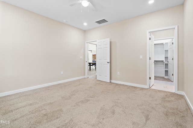 unfurnished bedroom featuring ceiling fan, a closet, light carpet, and a spacious closet