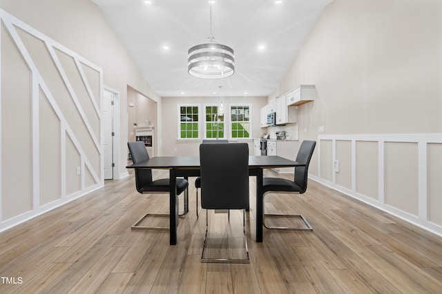 dining room featuring vaulted ceiling, a notable chandelier, a fireplace, and light hardwood / wood-style floors