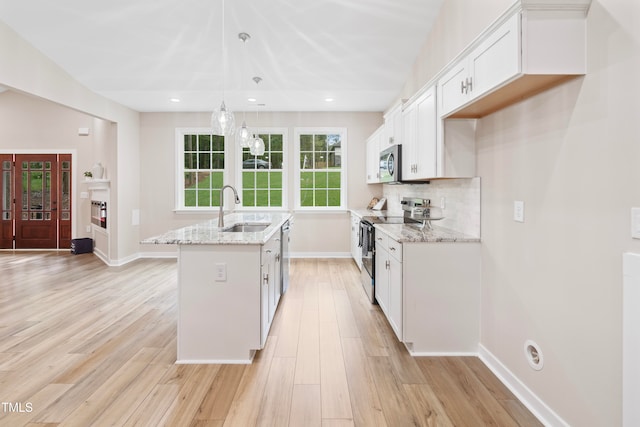 kitchen with sink, decorative light fixtures, a kitchen island with sink, white cabinetry, and appliances with stainless steel finishes