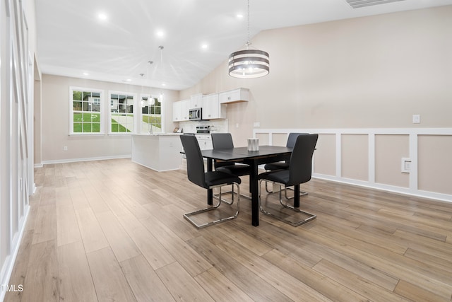 dining area featuring light hardwood / wood-style flooring, a chandelier, and lofted ceiling