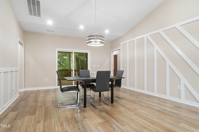 dining room with vaulted ceiling, an inviting chandelier, and light hardwood / wood-style floors