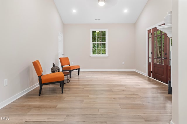 living area featuring light wood-type flooring, vaulted ceiling, and ceiling fan