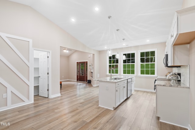 kitchen featuring lofted ceiling, white cabinetry, stainless steel appliances, a center island with sink, and decorative light fixtures