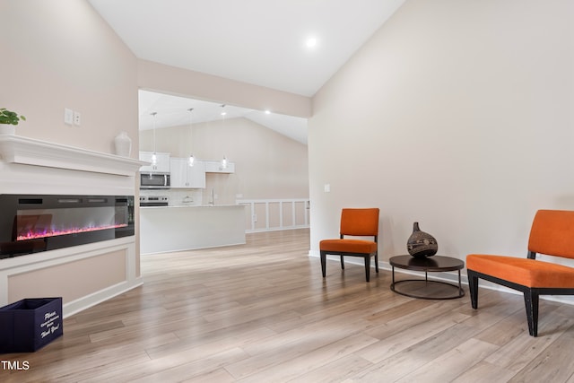 sitting room with light hardwood / wood-style flooring and high vaulted ceiling