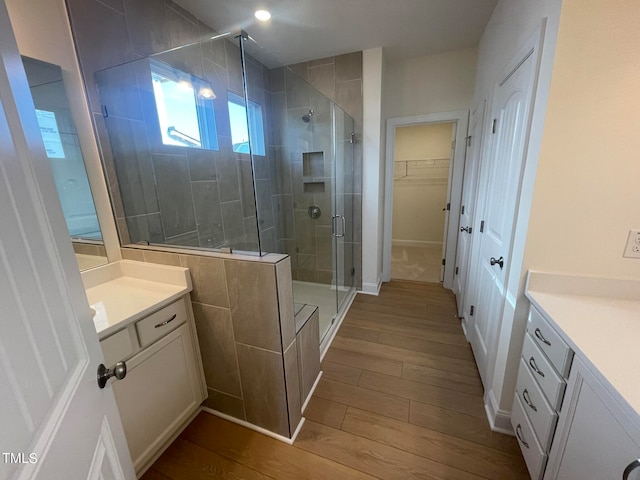 bathroom featuring walk in shower, wood-type flooring, and vanity