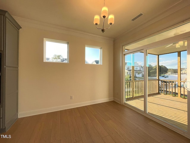 spare room with a notable chandelier, crown molding, and hardwood / wood-style flooring