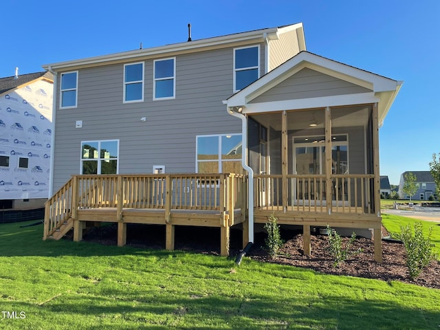 back of property featuring a wooden deck, a sunroom, and a lawn