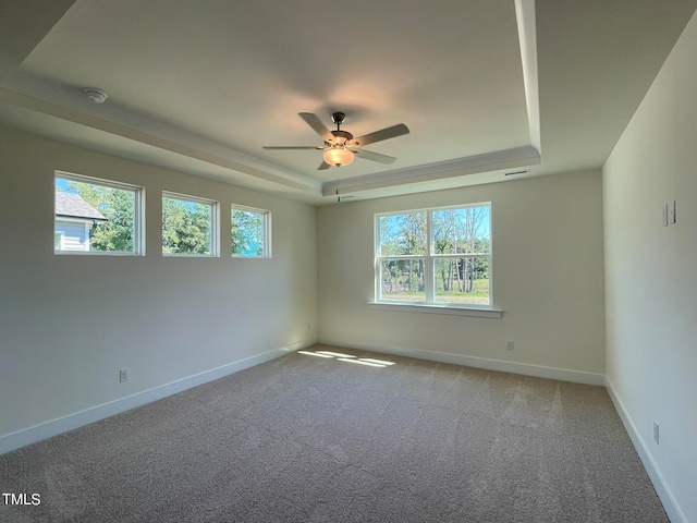 carpeted empty room with a tray ceiling and ceiling fan