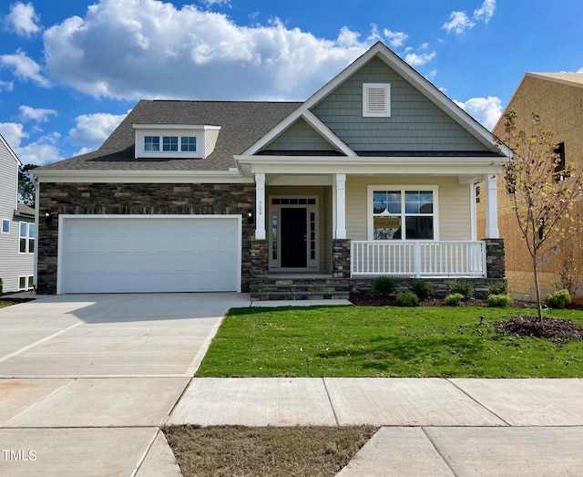 craftsman-style home with a porch, a garage, and a front yard