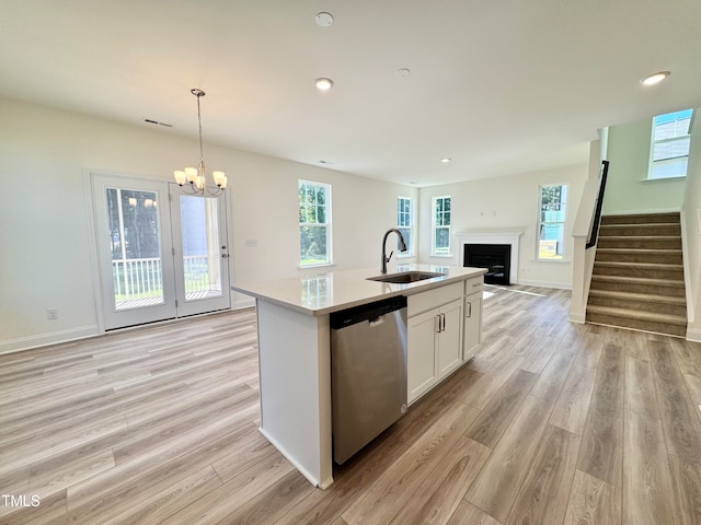 kitchen featuring pendant lighting, dishwasher, white cabinets, sink, and an island with sink