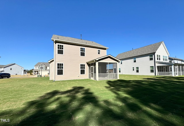 rear view of house with a sunroom and a yard