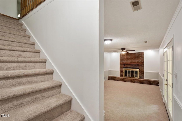 104 Argyle Ct, Garner, NC 27529 - stairs featuring ceiling fan, a brick fireplace, visible vents, and carpet flooring