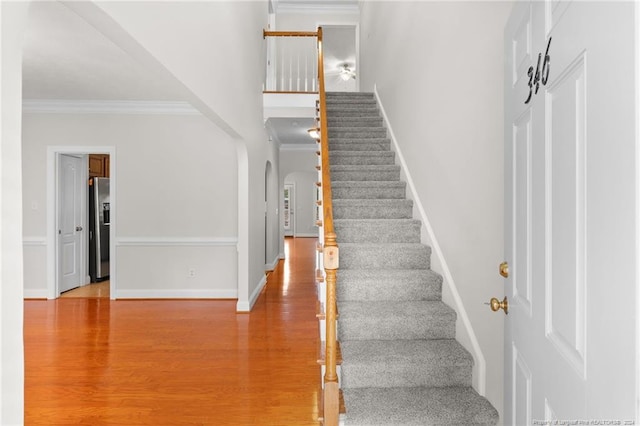 staircase with hardwood / wood-style floors and crown molding