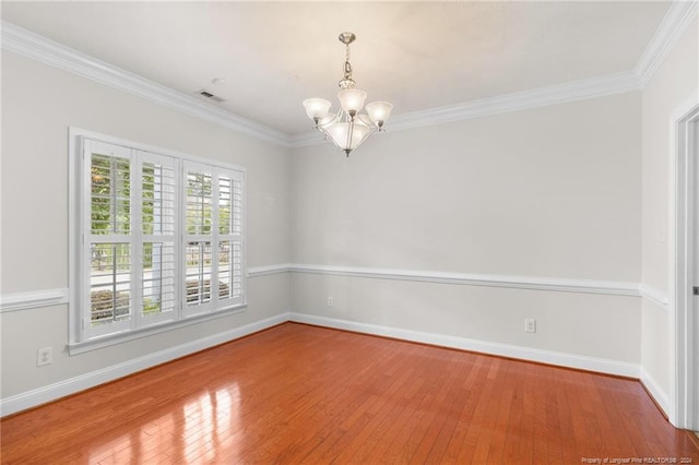 unfurnished room featuring wood-type flooring, an inviting chandelier, and crown molding