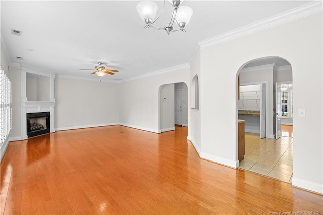 unfurnished living room featuring hardwood / wood-style floors, ceiling fan with notable chandelier, and crown molding