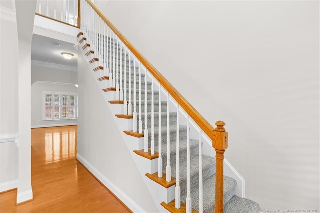 stairs with hardwood / wood-style floors and crown molding