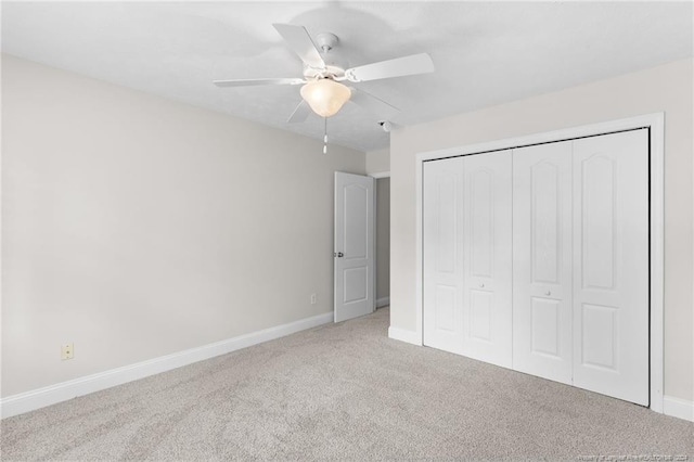 unfurnished bedroom with ceiling fan, light carpet, and a closet